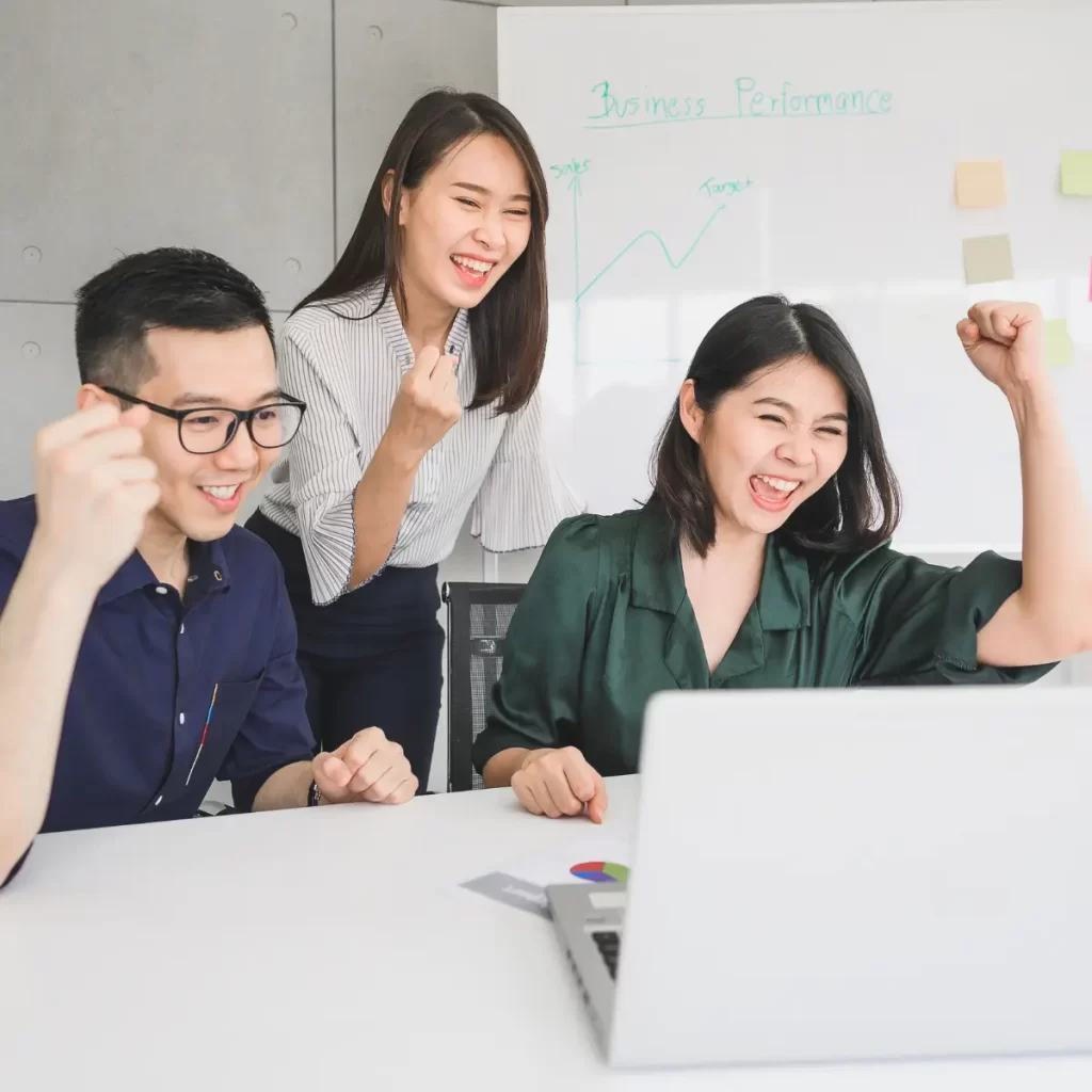 3 personas felices dos de ellas están sentadas y están viendo un computador 