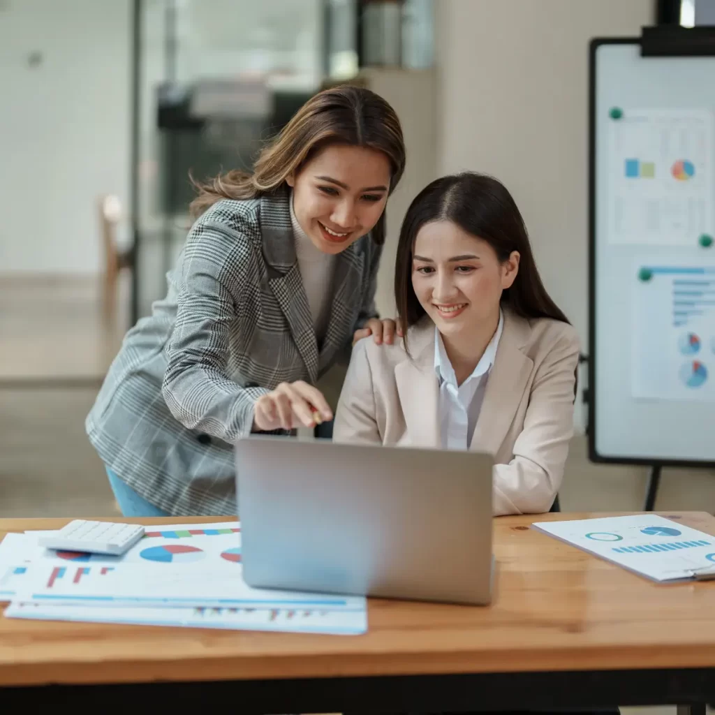 Imagen de dos mujeres mirando la pantalla de una computadora.