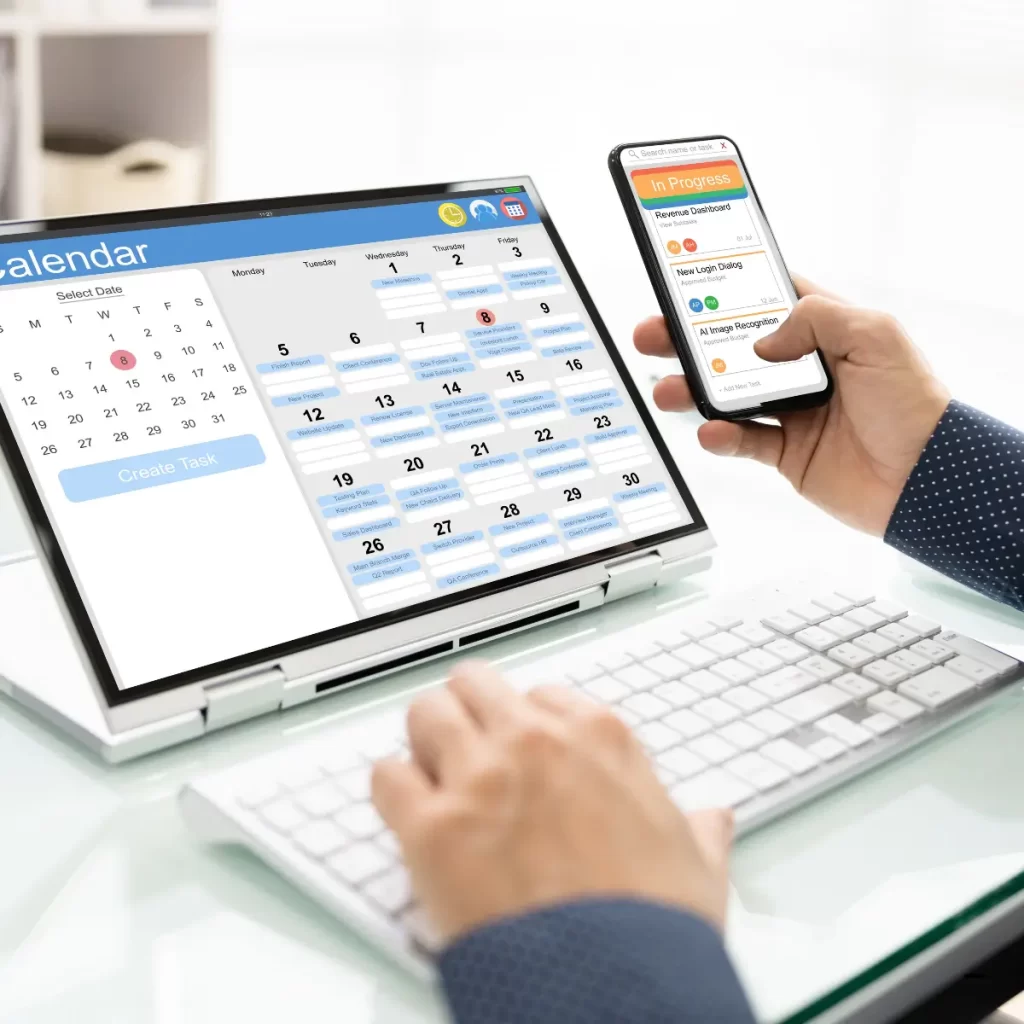 Imagen de una persona sentada frente a su computador y con un celular donde muestran un calendario