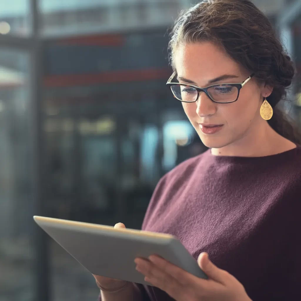 Imagen de una mujer con lentes con una table en la mano