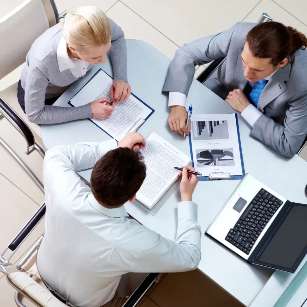 Imagen de 3 personas reunidas revisando informes