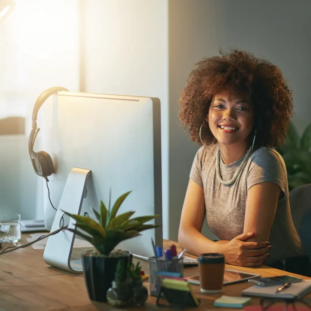 Una mujer frente a su computador y esta sonrriendo