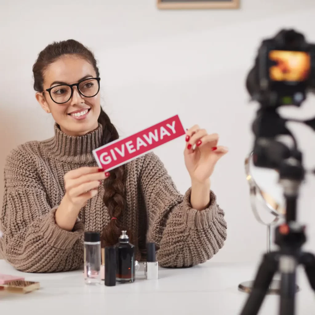 Imagen de una mujer grabando un video con la palabra GIVEAWAY en sus manos