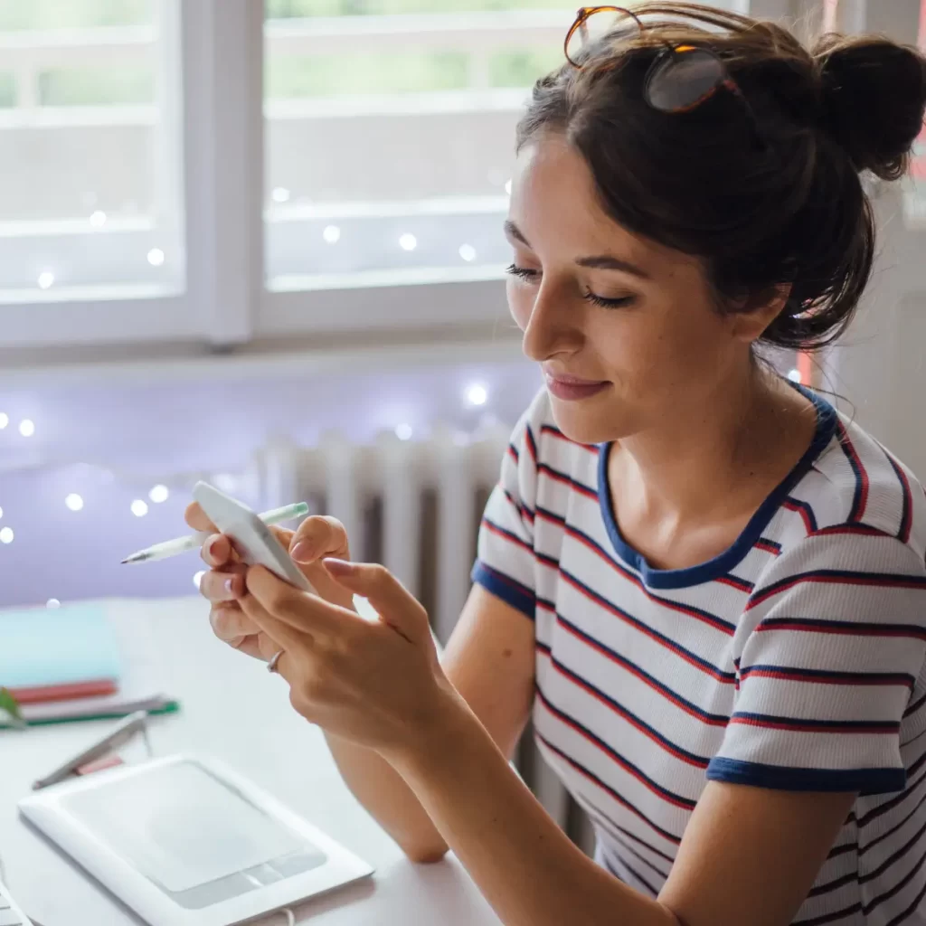 Imagen de una mujer con su celular en la mano lo cual hace referencia a Publicidad en redes sociales