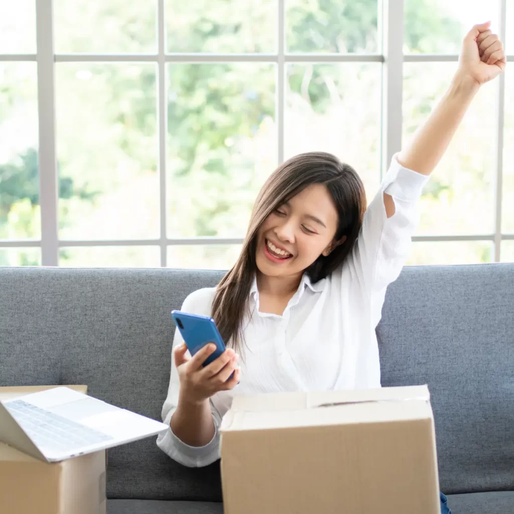 Imagen de una mujer con un celular en la mano la cual esta feliz esto hace referencia a la Analítica para ecommerce